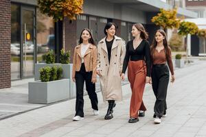 Gruppe von lächelnd und glücklich Teenager freunde tragen beiläufig Kleider Ausgaben Zeit zusammen, posieren und reden mit jeder andere in der Nähe von Hochschule Gebäude auf Herbst Tag. foto