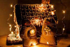 ein Lebkuchen Haus im das Rolle von ein Hochzeit Kuchen dekoriert mit ein Girlande, Lebkuchen Bräute sind Stehen Nächster zu Es. foto