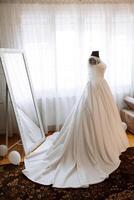 Schlafzimmer Innere mit Hochzeit Kleid bereit zum das Zeremonie. ein schön üppig Hochzeit Kleid auf ein Mannequin im ein Hotel Zimmer. foto