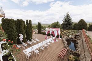 Hochzeit Dekor. viele Weiß Stühle und ein Weiß Weg. ein Weiß und Rosa Bogen dekoriert mit Blumen. Vorbereitung zum das Hochzeit Zeremonie. Feier foto