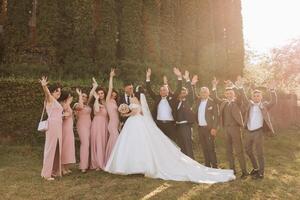 in voller Länge Porträt von das Jungvermählten und ihr freunde beim das Hochzeit. das Braut und Bräutigam mit Brautjungfern und freunde von das Bräutigam sind haben Spaß und Jubel beim das Hochzeit. foto