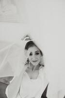 ein schön Brünette Braut mit ein Tiara im ihr Haar ist bekommen bereit zum das Hochzeit im ein schön Kleid im Boudoir Stil. Nahansicht Hochzeit Porträt, Foto. foto