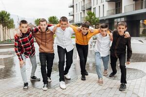 Gruppe von lächelnd und glücklich Teenager freunde tragen beiläufig Kleider Ausgaben Zeit zusammen, posieren und reden mit jeder andere in der Nähe von Hochschule Gebäude auf Herbst Tag. foto