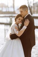 Winter Hochzeit. ein glücklich Paar im Hochzeit Kleider sind umarmen und lächelnd im ein Winter Park bedeckt mit Schnee auf ihr Hochzeit Tag. Winter Liebe Geschichte von ein schön Paar im schneebedeckt Winter Wetter foto