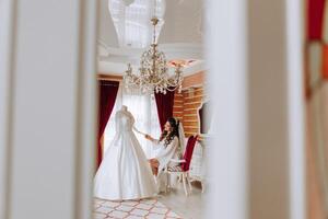 ein glücklich Braut ist vorbereiten zum ihr luxuriös Hochzeit im ein Hotel Zimmer, mit ein Hochzeit Kleid auf ein Mannequin nahe. Porträt von ein Frau mit modisch Haar, bilden und ein Lächeln im ein Dressing Kleid. foto