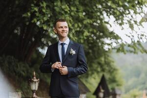 das Bräutigam im ein schwarz passen passt sich an seine Jacke, posiert gegen das Hintergrund von ein Grün Baum. Hochzeit Porträt. foto