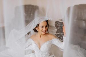 Hochzeit Porträt. das Braut im ein elegant Hochzeit Kleid posiert eingewickelt im ein Schleier. Morgen von das Braut. schön Haar und bilden foto