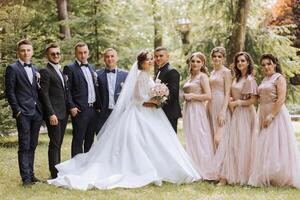 in voller Länge Porträt von das Jungvermählten und ihr freunde beim das Hochzeit. das Braut und Bräutigam mit Brautjungfern und freunde von das Bräutigam sind haben Spaß und Jubel beim das Hochzeit. foto