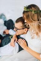 jung Mann und Frau Laufen Lügen auf Schnee, Lachen, täuschen um, haben Spaß spielen Schneebälle. europäisch Winter Hochzeit. Porträt von das Braut und Bräutigam im das Schnee foto