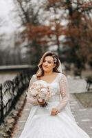 Porträt von ein schön Braut mit ein Hochzeit Strauß von Blumen, attraktiv Frau im ein Hochzeit Kleid mit ein lange Schleier. glücklich Braut Frau. Braut mit Hochzeit bilden und Frisur. Winter Hochzeit foto