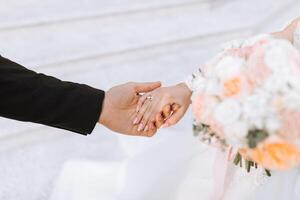 das Bräutigam zärtlich hält das Braut Hand nach Platzierung ein Hochzeit Ring auf ihr Finger beim ein Hochzeit Zeremonie. ein schön Hochzeit im das kalt Jahreszeit. foto