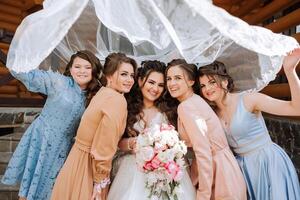 Gruppe Porträt von das Braut und Brautjungfern. ein Braut im ein Hochzeit Kleid und Brautjungfern im schön Kleider halt das Braut Strauß auf das Hochzeit Tag. foto