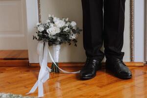 ein elegant Mann trägt schwarz Leder formal Schuhe. binden Schuhe. Geschäft Mann binden Schnürsenkel auf das Boden. oben schließen das Bräutigam ist vorbereiten zum das Hochzeit. foto