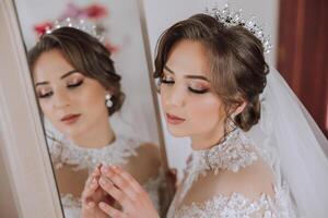 Mode Foto von ein schön Braut mit dunkel Haar im ein elegant Hochzeit Kleid und atemberaubend bilden im das Zimmer auf das Morgen von das Hochzeit. das Braut ist vorbereiten zum das Hochzeit