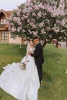 Hochzeit. Liebe und Paar im Garten zum Hochzeit. feiern das Zeremonie und Engagement. speichern das Datum. Vertrauen. das Braut und Bräutigam Umarmung gegen das Hintergrund von ein Frühling Blühen Baum. foto