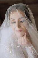 Mode Foto von ein schön Braut mit dunkel Haar im ein elegant Hochzeit Kleid und atemberaubend bilden im das Zimmer auf das Morgen von das Hochzeit. das Braut ist vorbereiten zum das Hochzeit