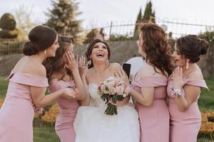 Gruppe Porträt von das Braut und Brautjungfern. Braut im ein Hochzeit Kleid und Brautjungfern im Rosa oder Pulver Kleider und halten stilvoll Blumensträuße auf das Hochzeit Tag. foto