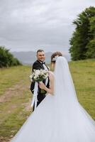 Hochzeit. Liebe und Paar im Garten zum Hochzeit. Feier von Zeremonie und Engagement. speichern das Datum. Vertrauen das Bräutigam umarmt das Braut im das Berge auf das Hintergrund von das Wald foto