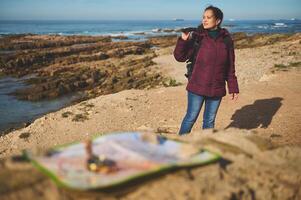 aktiv weiblich Abenteurer Reisender suchen in das Entfernung durch Fernglas, Stehen auf das Felsen durch Meer. foto