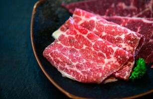 geschnitten Oberseite wagyu Rindfleisch zum Yakiniku auf Teller auf schwarz Hintergrund, Prämie japanisch Fleisch foto