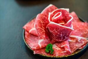 geschnitten wagyu marmoriert Rindfleisch zum Yakiniku auf Teller auf schwarz Hintergrund, foto