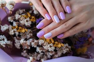 Damen Hände mit ein modisch sehr peri Maniküre gegen das Hintergrund von getrocknet Blumen. Frühling Sommer Nagel Design foto
