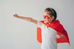 komisch wenig Super Held Mädchen im ein rot Mantel. Superheld Konzept. wenig Kind spielen Held im das Kinder foto