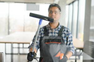 männlich Fachmann Reinigung Bedienung Arbeiter reinigt das Fenster und Geschäft Fenster von ein Geschäft mit Besondere Ausrüstung foto