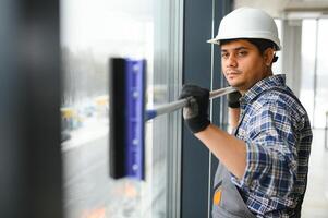 männlich Fachmann Reinigung Bedienung Arbeiter reinigt das Fenster und Geschäft Fenster von ein Geschäft mit Besondere Ausrüstung foto