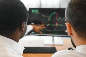 zwei erfolgreich Händler Sitzung im Büro, Überprüfung Kryptowährung Information Daten auf Finanzen Markt Graph, zeigen auf Monitor foto