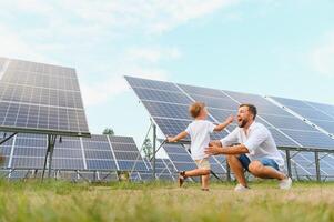 lächelnd Vater und seine wenig Kind auf Hintergrund von Solar- Tafeln. jung Vater genießen Ausgaben Zeit mit seine Sohn. glücklich Familie von zwei auf Hintergrund von Solar- Tafeln. foto