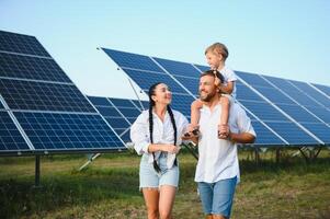 begeistert Vater zeigen Potenzial von Alternative Energie. zeitgenössisch Familie suchen beim Neu Solar- Bahnhof Sie gekauft. Seite Aussicht von glücklich Eltern und interessiert Kind Nächster zu Solar- Paneele foto
