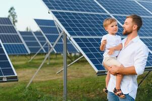 glücklich Vater und seine wenig Sohn sind Gehen in der Nähe von das Solar- Tafeln. das Konzept von Grün Energie. foto