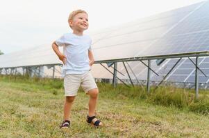 ein wenig Junge ist haben Spaß in der Nähe von das Solar- Tafeln. das Konzept von Solar- Energie. foto