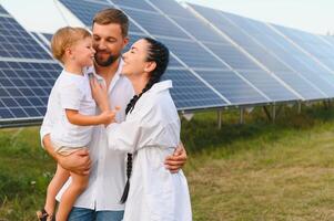 jung Familie von drei ist duckte sich in der Nähe von Photovoltaik Solar- Tafel, wenig Junge und Eltern. modern Familie Konzept. das Konzept von Grün Energie foto