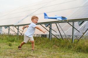 ein wenig Junge ist haben Spaß in der Nähe von das Solar- Tafeln. das Konzept von Solar- Energie. foto