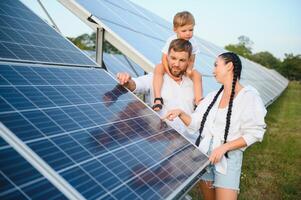 begeistert Vater zeigen Potenzial von Alternative Energie. zeitgenössisch Familie suchen beim Neu Solar- Bahnhof Sie gekauft. Seite Aussicht von glücklich Eltern und interessiert Kind Nächster zu Solar- Paneele foto