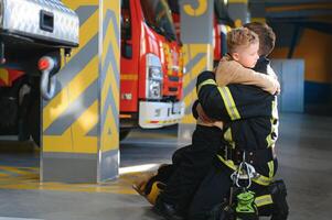 ein Feuerwehrmann nehmen ein wenig Kind Junge zu speichern ihn. Feuer Motor Auto auf Hintergrund foto