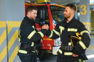 Gruppe von Feuerwehrleute beim das Notfall Fahrzeug im das Feuer Bahnhof foto