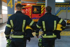 Gruppe von Feuerwehrleute beim das Notfall Fahrzeug im das Feuer Bahnhof foto