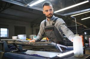 drucken Arbeiter versuchen zu Fix das Problem auf Computer zu Teller Maschine im Drucken Geschäft foto