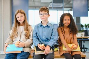 gemischtrassig Schulkinder haben Mittagessen beim das Schreibtisch während ein brechen im Schule foto