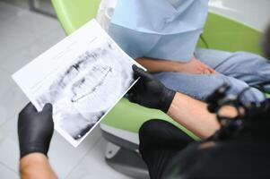 Zahnarzt zeigt an ein Röntgen von Kiefer. Zahnarzt Dienstleistungen Konzept foto