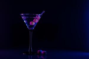 Martini Glas und Oliven auf ein schwarz Hintergrund mit Neon- Beleuchtung foto