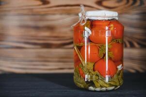 hausgemacht eingelegt Tomaten im Glas Gläser auf rustikal hölzern Hintergrund. fermentiert Tomaten im transparent Glas. hausgemacht Dosen- Tomaten. foto