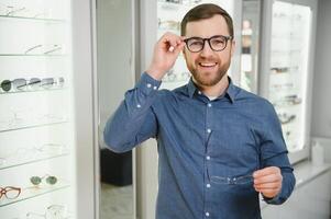 Schuss von ein gut aussehend bärtig Mann versuchen auf Neu Brille beim das Brillen shop.man Kauf Brillen.Gesundheit, Sehvermögen, Vision, Mode, Einkaufen foto