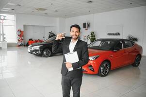 indisch heiter Auto Verkäufer zeigen Neu Auto beim Ausstellungsraum foto