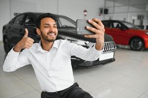 gut aussehend indisch Mann nehmen ein Selfie mit Auto Schlüssel zu seine Neu Automobil beim das Händler Ausstellungsraum Copyspace Technologie Sozial Medien Teilen Positivität Lebensstil Reisen Tourismus. foto