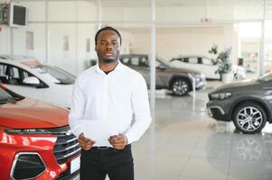 Autos Händler Konzept. Auto Verkäufer afro Mann Stehen im Automobil Center foto