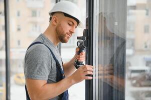 Konstruktion Arbeiter mit bohren während Installation Fenster drinnen foto